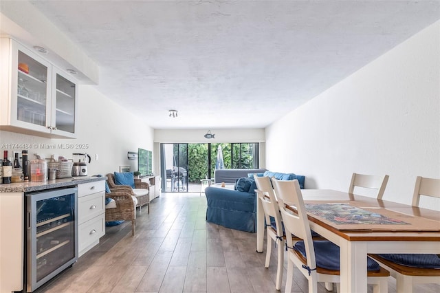 dining area with indoor bar, beverage cooler, and light hardwood / wood-style flooring