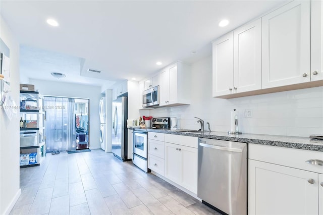 kitchen featuring stone counters, sink, white cabinets, backsplash, and stainless steel appliances