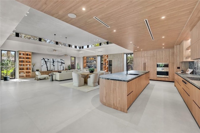 kitchen featuring a large island, light brown cabinetry, a healthy amount of sunlight, and wood ceiling