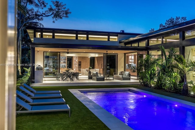 back house at dusk featuring an outdoor living space, ceiling fan, and a patio area