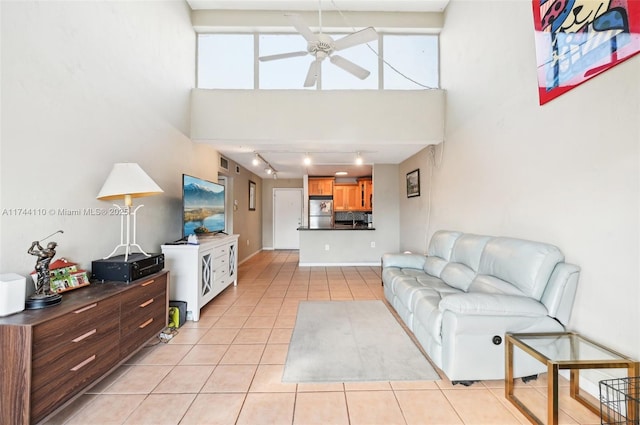 living room with a high ceiling, rail lighting, light tile patterned floors, and ceiling fan