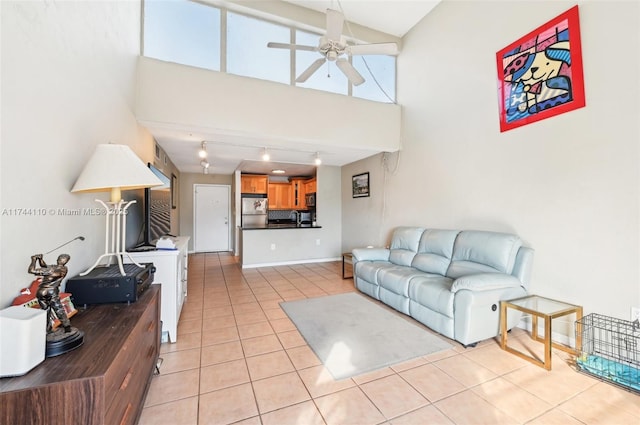 tiled living room featuring a towering ceiling, track lighting, and ceiling fan