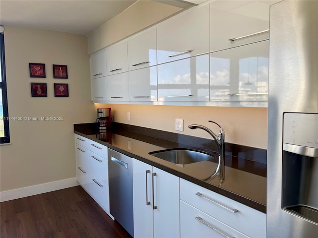 kitchen with appliances with stainless steel finishes, sink, white cabinets, and dark hardwood / wood-style floors