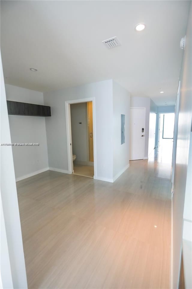 empty room with electric panel and light wood-type flooring