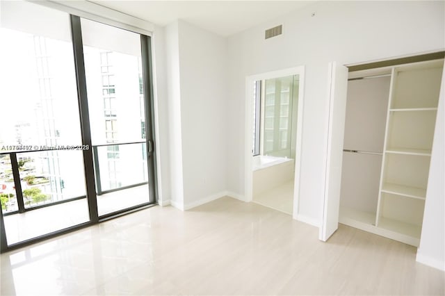 unfurnished bedroom featuring a wall of windows and connected bathroom