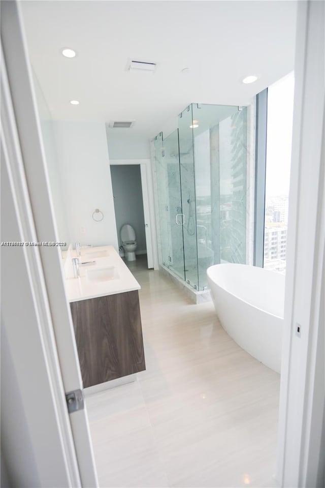 full bathroom featuring vanity, toilet, and separate shower and tub