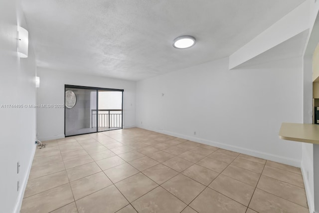 tiled empty room featuring a textured ceiling