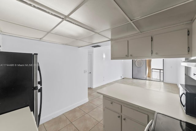 kitchen featuring stainless steel appliances, light tile patterned flooring, and a drop ceiling