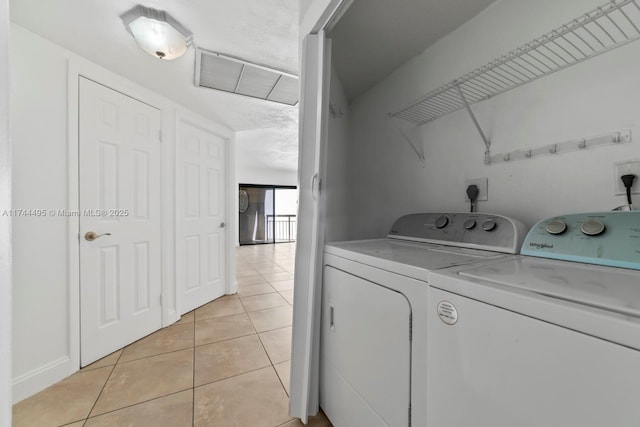 clothes washing area featuring washing machine and dryer and light tile patterned floors