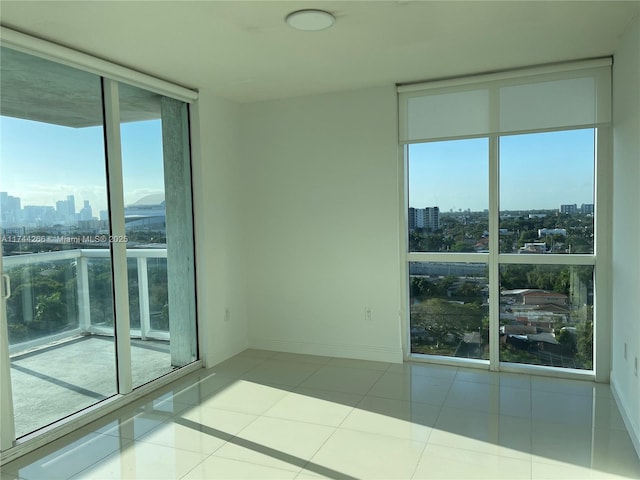 empty room with tile patterned flooring, a view of city, a wall of windows, and baseboards