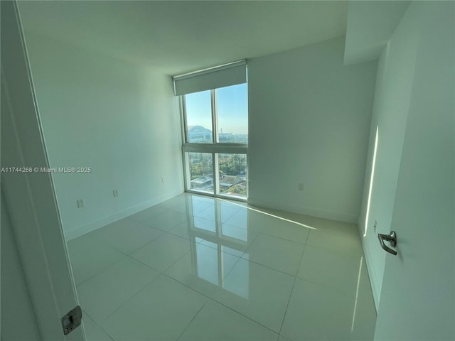 tiled spare room with baseboards and a wall of windows