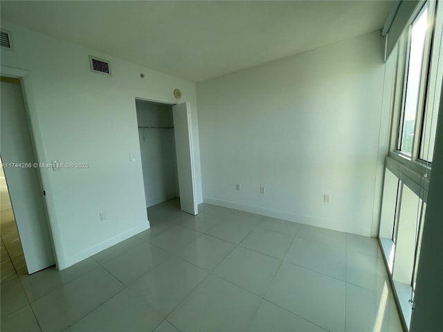 unfurnished bedroom featuring light tile patterned flooring, visible vents, baseboards, and a closet