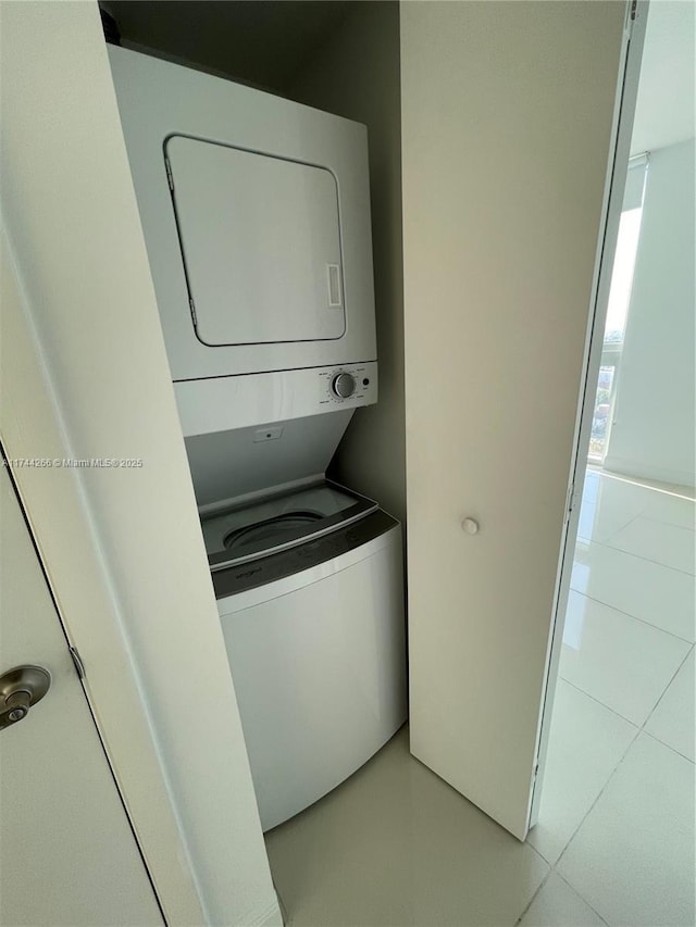 laundry room with light tile patterned floors, stacked washer and clothes dryer, and laundry area