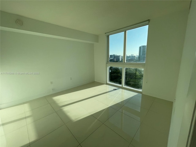 tiled empty room featuring baseboards and a city view