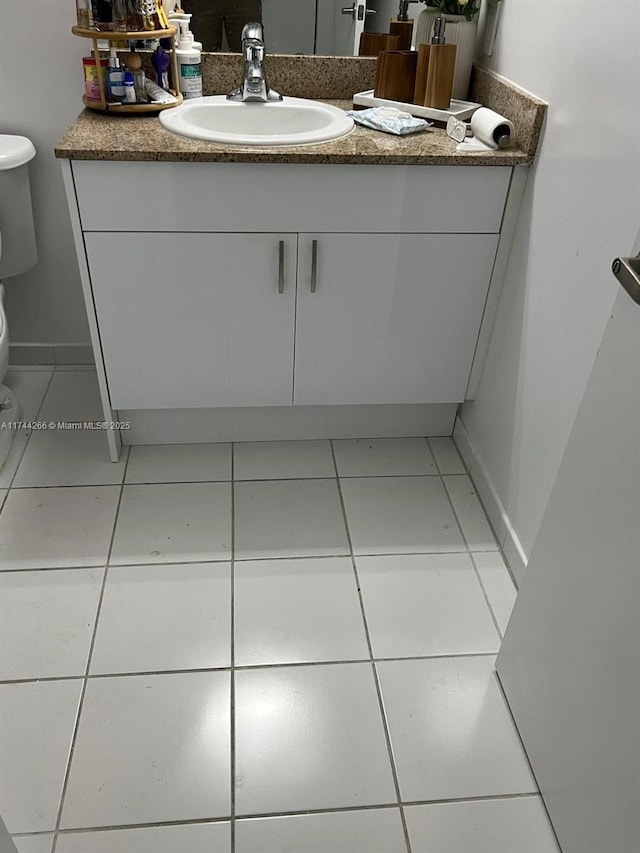 half bath featuring tile patterned floors, toilet, and vanity
