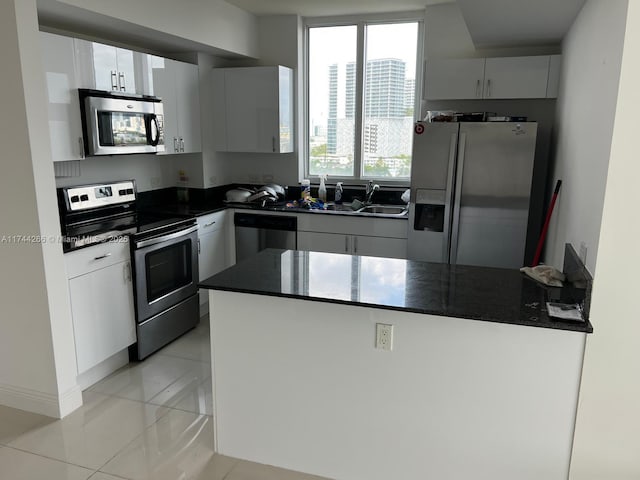 kitchen featuring a sink, a peninsula, white cabinetry, baseboards, and appliances with stainless steel finishes
