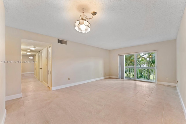 tiled spare room with a textured ceiling