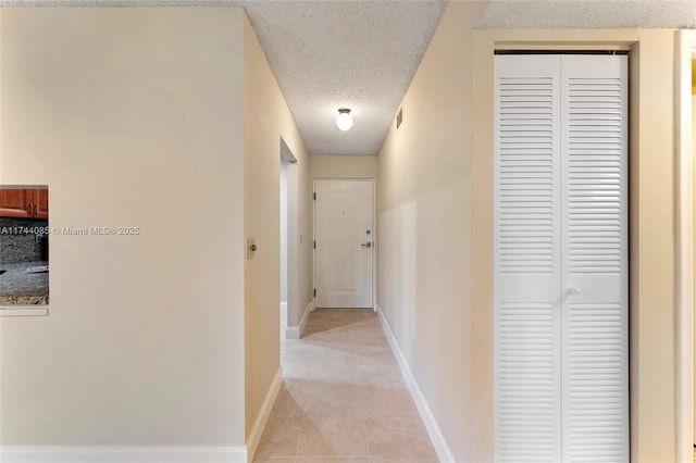 hallway with light tile patterned floors and a textured ceiling