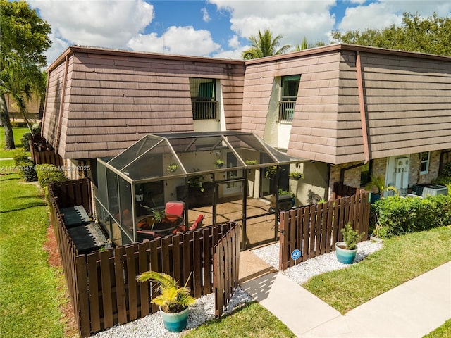 view of front facade featuring a front lawn, central AC, a patio, and a lanai