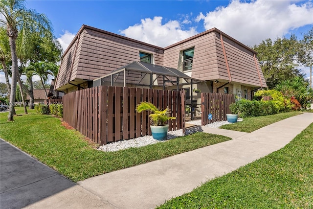 view of home's exterior featuring glass enclosure and a lawn