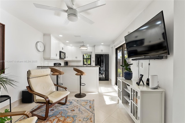 kitchen with backsplash, a kitchen breakfast bar, black appliances, kitchen peninsula, and white cabinets