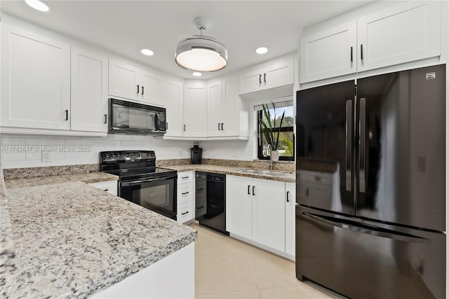 kitchen with black appliances, sink, light stone counters, white cabinets, and decorative backsplash