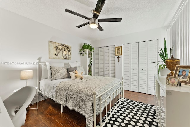 bedroom with ceiling fan, multiple closets, dark hardwood / wood-style floors, and a textured ceiling