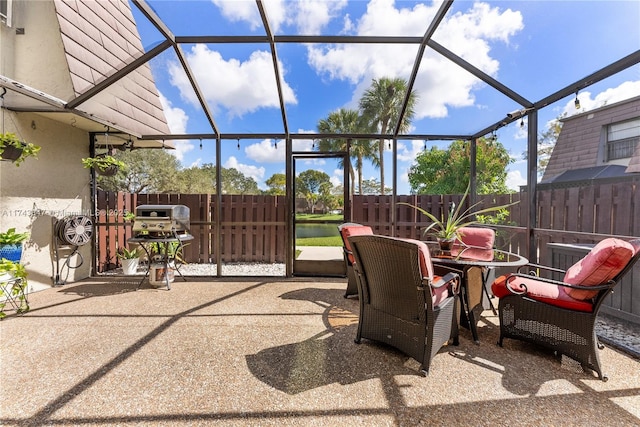 view of patio / terrace with a water view, a lanai, and grilling area