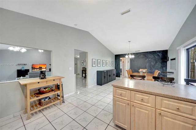 kitchen with lofted ceiling, hanging light fixtures, light brown cabinetry, and a chandelier