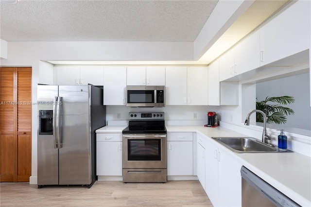 kitchen featuring sink, stainless steel appliances, white cabinets, and light wood-type flooring