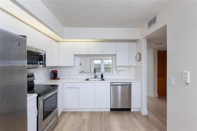 kitchen featuring stainless steel appliances, white cabinetry, sink, and light wood-type flooring