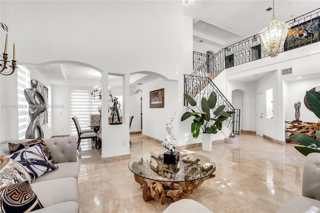 living room with a notable chandelier, a tray ceiling, and a towering ceiling