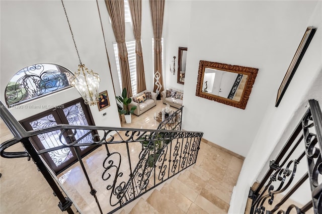 staircase featuring an inviting chandelier, french doors, and a high ceiling