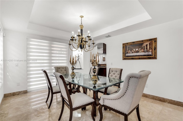 dining area featuring an inviting chandelier and a tray ceiling