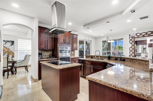 kitchen featuring sink, light stone counters, island range hood, a center island, and hanging light fixtures