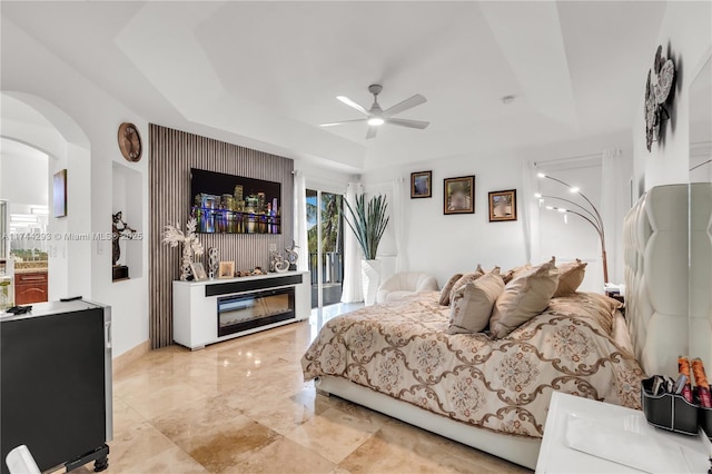 bedroom with a fireplace, access to outside, a raised ceiling, and ceiling fan