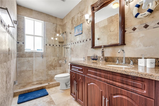 bathroom featuring vanity, toilet, a shower with door, and tile walls