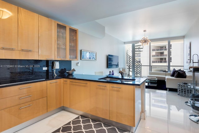 kitchen featuring sink, dark stone counters, light tile patterned floors, a notable chandelier, and kitchen peninsula