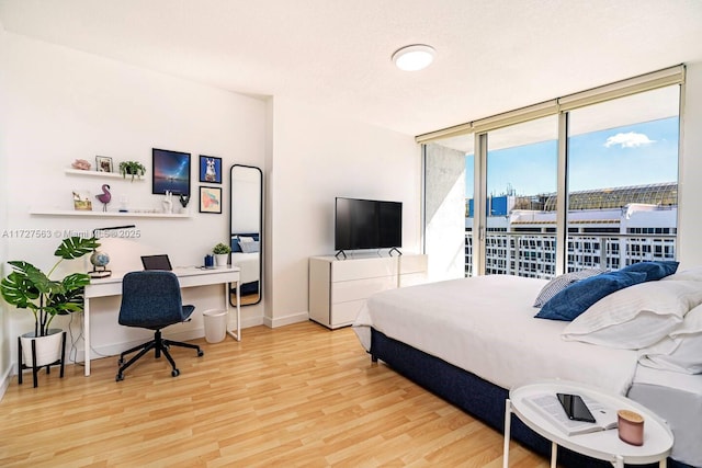 bedroom with access to outside, expansive windows, and light wood-type flooring