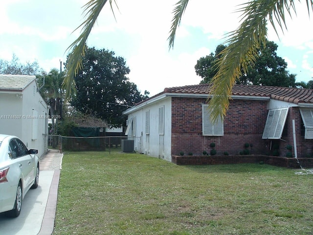 view of side of property featuring central AC unit and a lawn