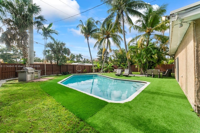 view of swimming pool featuring a grill and a yard