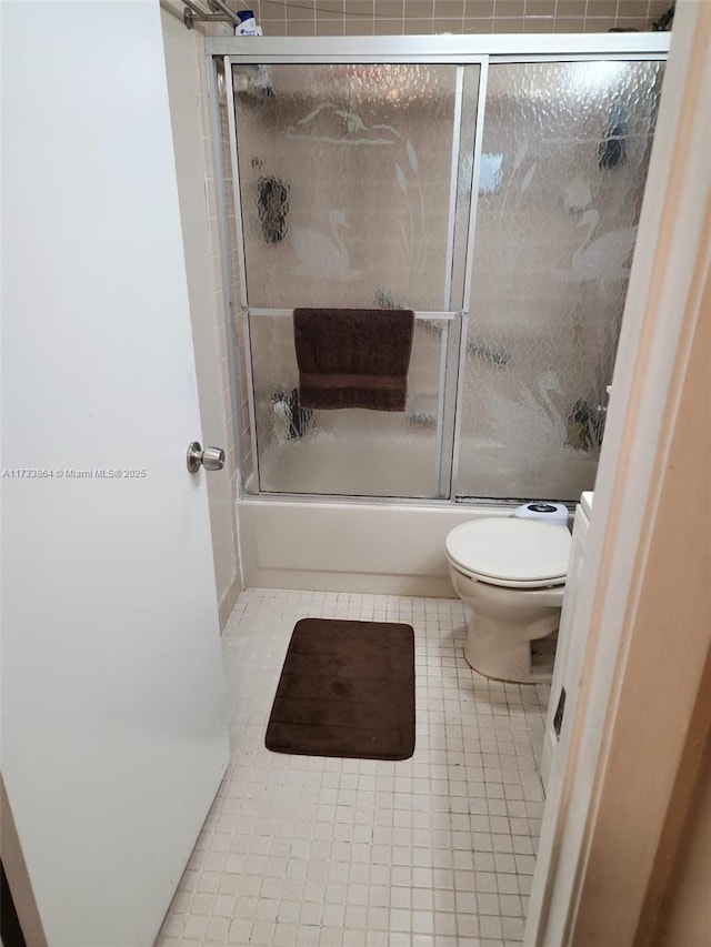 bathroom featuring enclosed tub / shower combo, tile patterned floors, and toilet