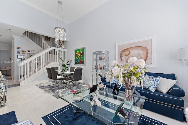 living room featuring hardwood / wood-style flooring, a towering ceiling, ornamental molding, and a chandelier