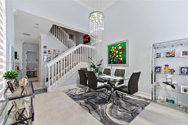 dining space featuring hardwood / wood-style flooring, ornamental molding, a high ceiling, and an inviting chandelier