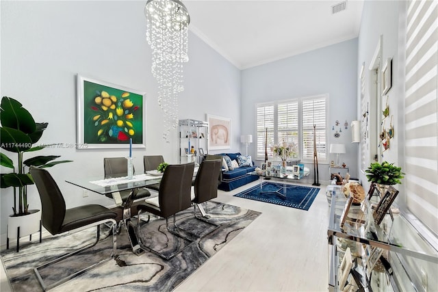 home office featuring an inviting chandelier, a towering ceiling, ornamental molding, and hardwood / wood-style flooring