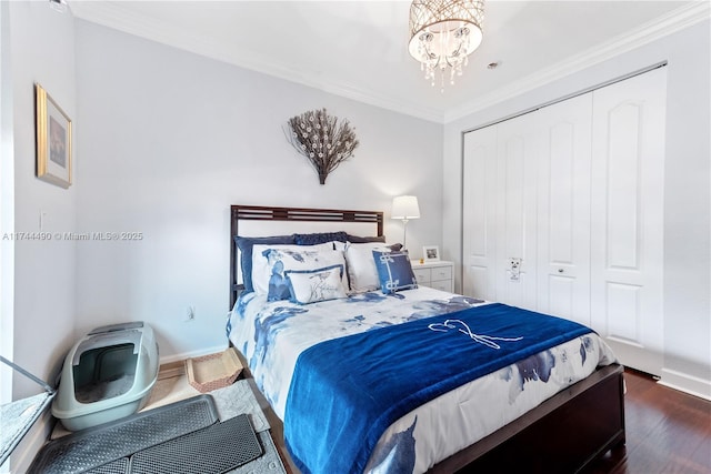 bedroom with crown molding, dark wood-type flooring, a chandelier, and a closet