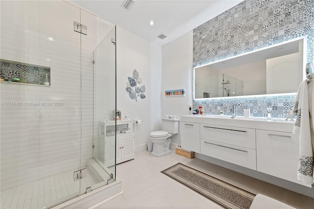 bathroom featuring vanity, toilet, and a shower with door