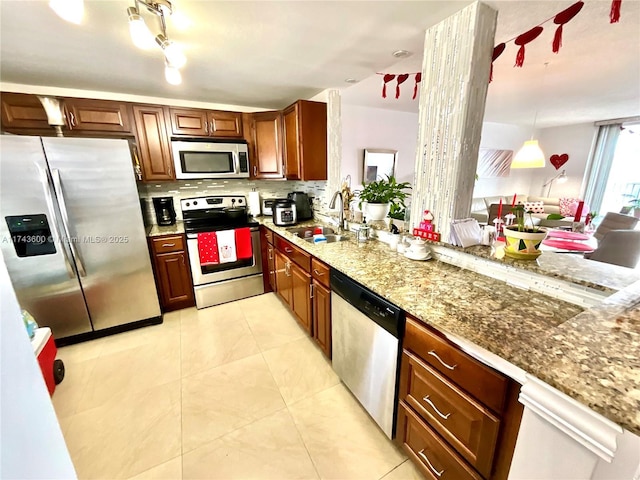 kitchen featuring pendant lighting, stainless steel appliances, sink, and light stone counters