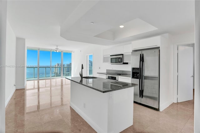 kitchen featuring floor to ceiling windows, sink, a water view, stainless steel appliances, and white cabinets