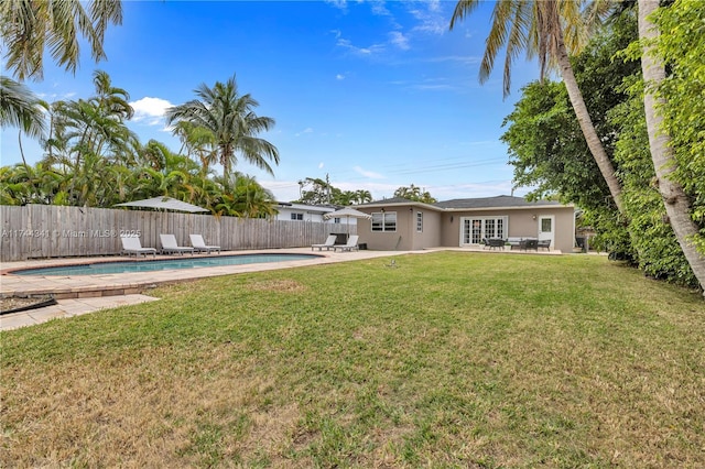 view of yard featuring a patio, a fenced in pool, and french doors